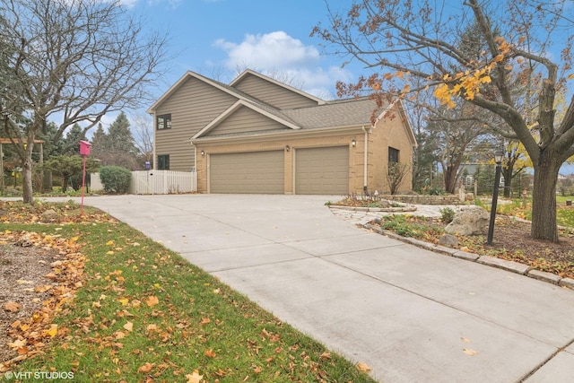 view of front of home with driveway, fence, roof with shingles, an attached garage, and brick siding