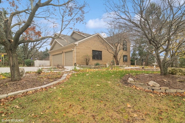 view of home's exterior featuring brick siding, fence, concrete driveway, a yard, and a garage