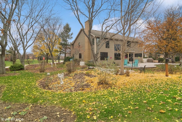 back of property with a lawn, a chimney, and a patio area