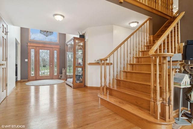 foyer entrance with stairway, wood finished floors, and baseboards