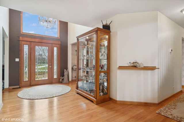 entrance foyer with baseboards, lofted ceiling, and wood finished floors