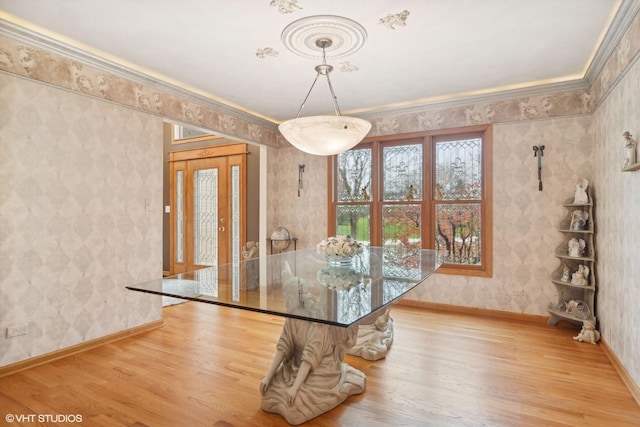 unfurnished dining area featuring wallpapered walls, baseboards, light wood finished floors, and ornamental molding