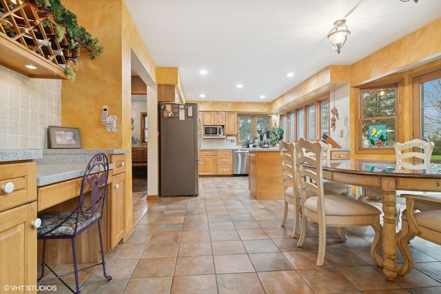 kitchen with decorative backsplash, light countertops, built in desk, and appliances with stainless steel finishes