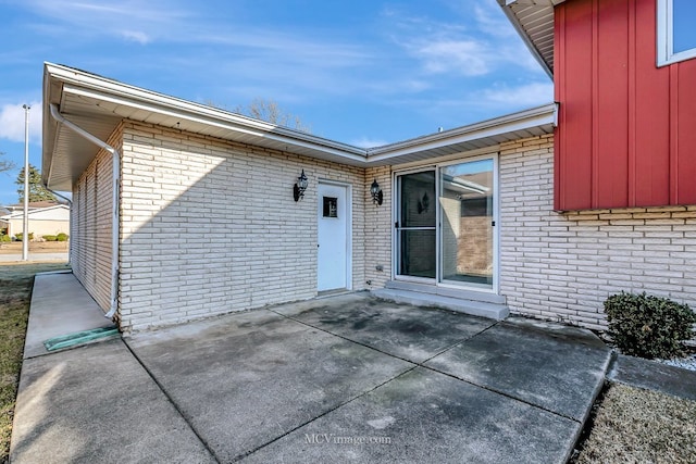 doorway to property featuring brick siding and a patio area