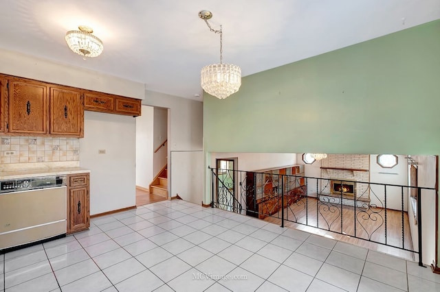 kitchen with backsplash, an inviting chandelier, brown cabinetry, light countertops, and dishwashing machine