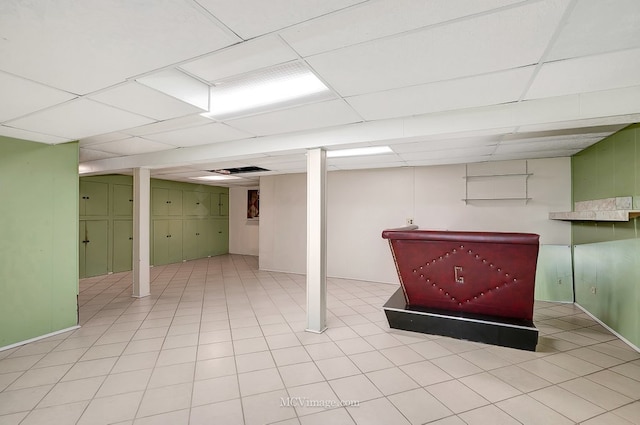 finished below grade area featuring tile patterned floors and a paneled ceiling