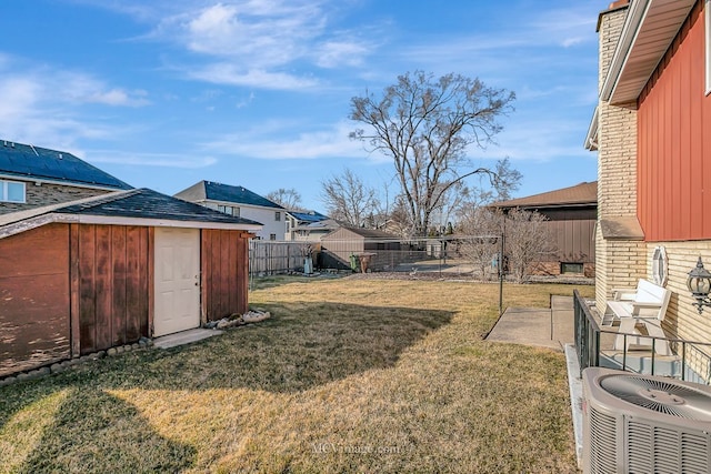 view of yard with an outbuilding, central AC, a fenced backyard, and a storage shed