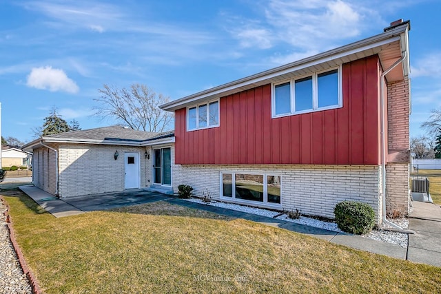 split level home featuring a front yard and brick siding