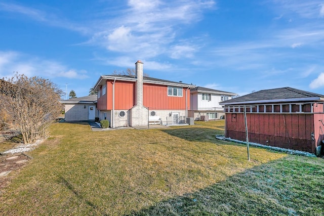 back of property featuring brick siding, board and batten siding, a chimney, and a yard