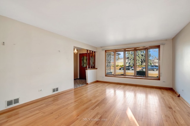 empty room with baseboards, visible vents, and light wood-type flooring