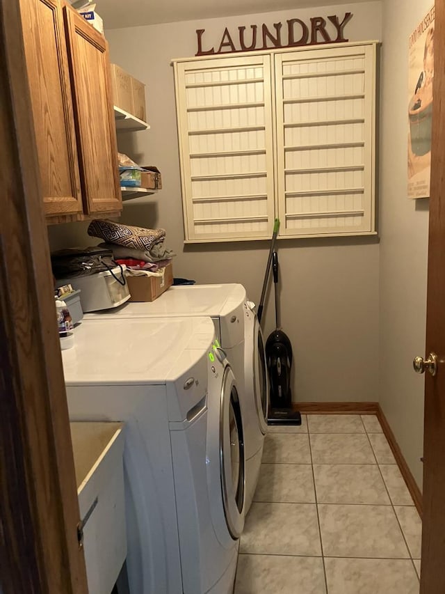 washroom with light tile patterned flooring, cabinet space, baseboards, and washer and clothes dryer