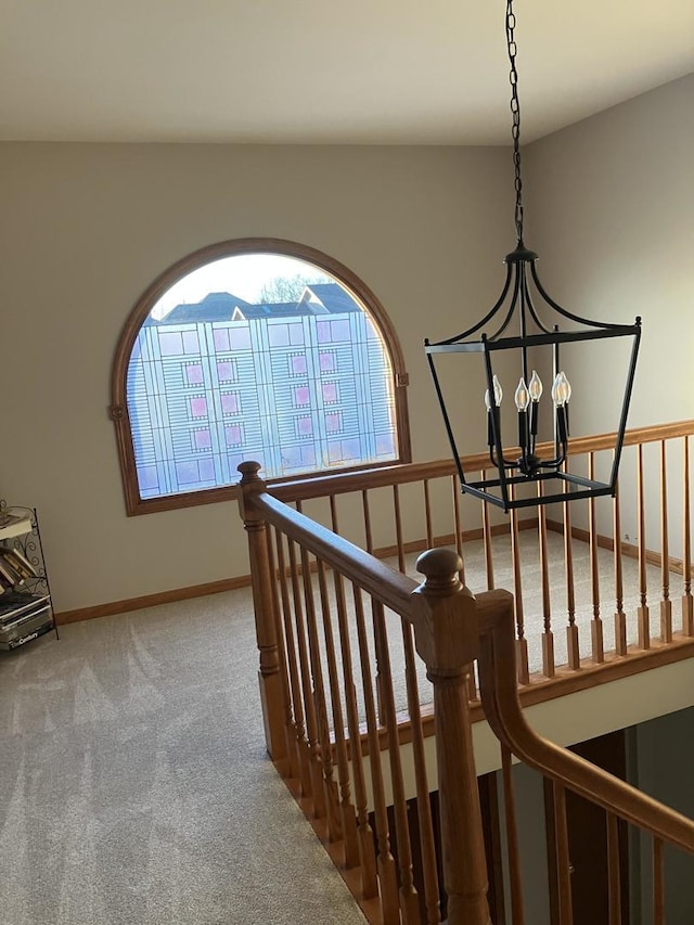 staircase featuring baseboards, carpet floors, and a chandelier