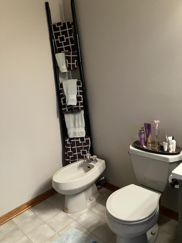 half bath featuring baseboards, a bidet, toilet, and tile patterned flooring