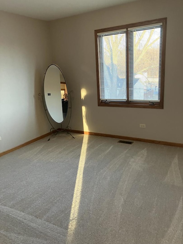 spare room featuring visible vents, baseboards, and light carpet