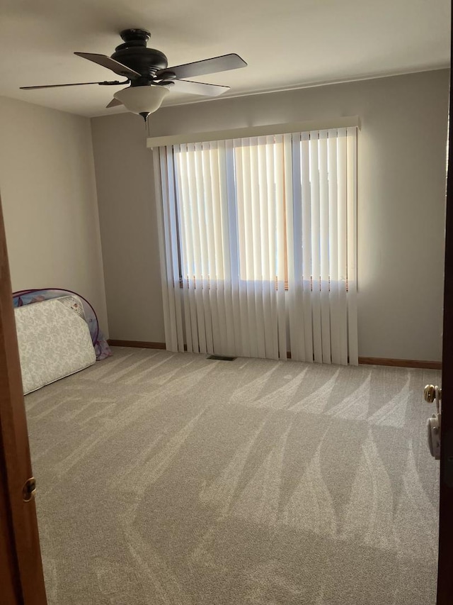 carpeted empty room with visible vents and ceiling fan