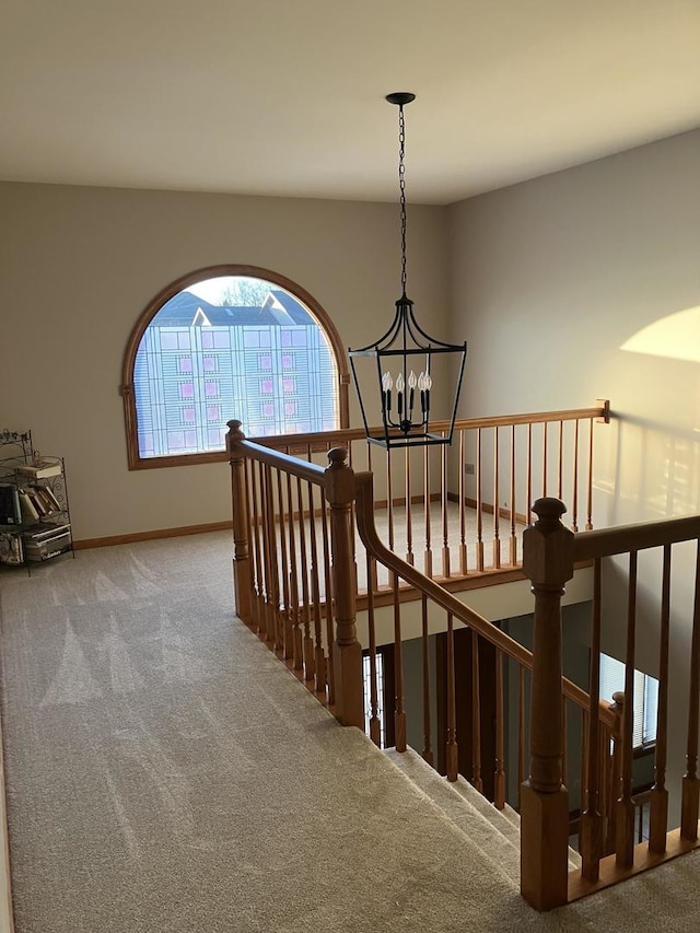 staircase with baseboards, carpet floors, and a chandelier