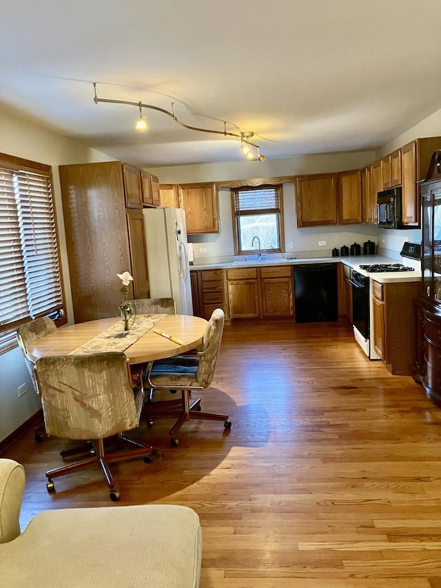 kitchen featuring black appliances, brown cabinetry, light wood-style floors, and a sink