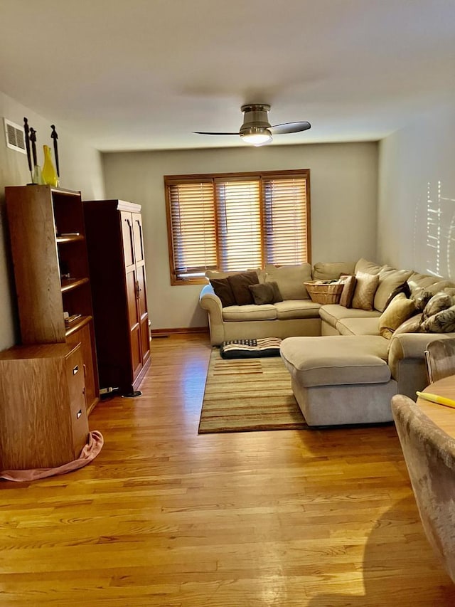 living area featuring light wood-style floors, visible vents, and ceiling fan