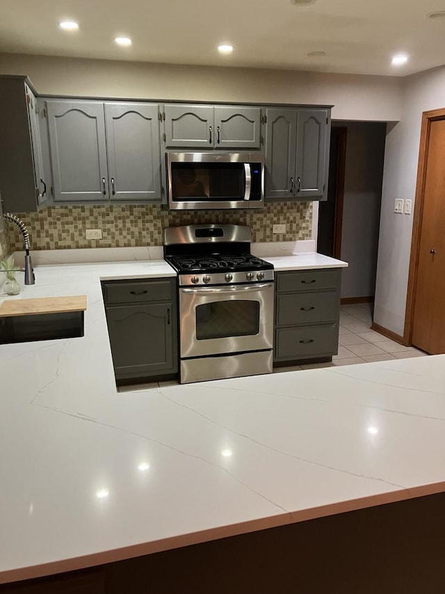 kitchen featuring recessed lighting, gray cabinets, a sink, appliances with stainless steel finishes, and backsplash