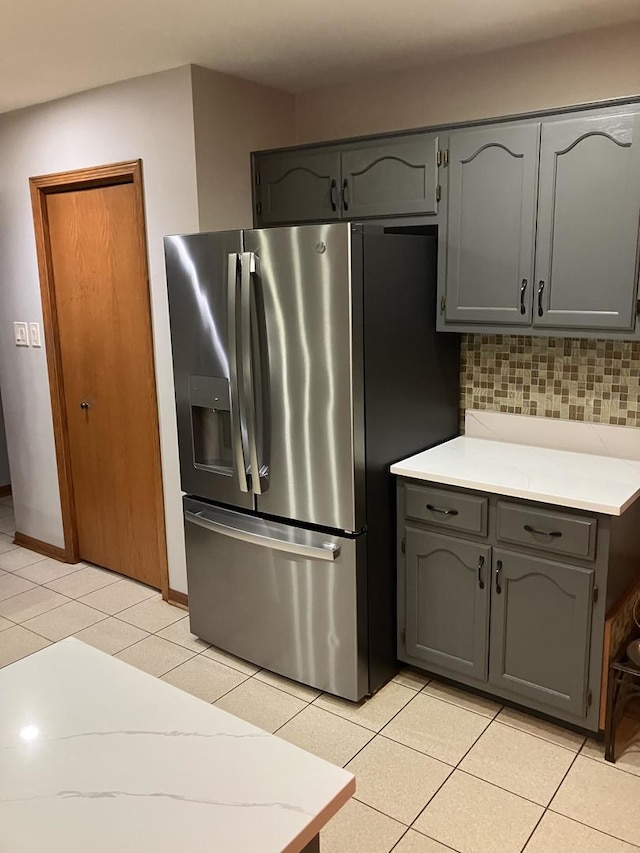 kitchen with gray cabinets, tasteful backsplash, stainless steel fridge with ice dispenser, light countertops, and light tile patterned floors