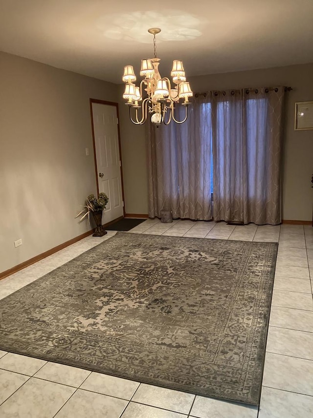 unfurnished dining area featuring tile patterned floors, a notable chandelier, and baseboards