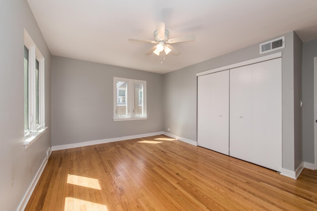 unfurnished bedroom with visible vents, a closet, light wood finished floors, baseboards, and ceiling fan