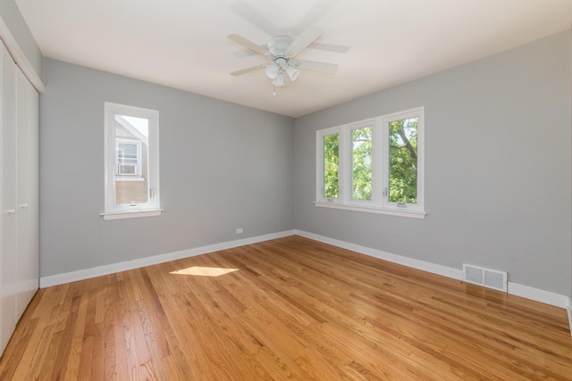 empty room with a ceiling fan, light wood-style flooring, baseboards, and visible vents