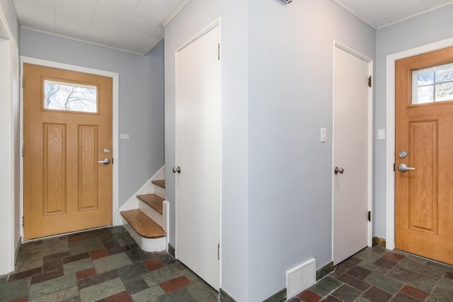 foyer entrance featuring stairs, crown molding, stone finish floor, and visible vents