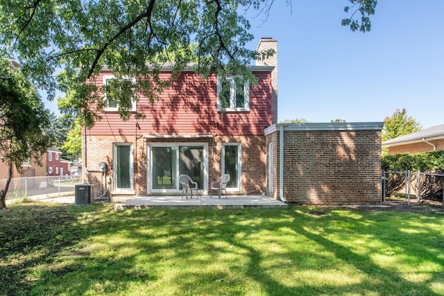 rear view of house with a yard, a chimney, a fenced backyard, and brick siding