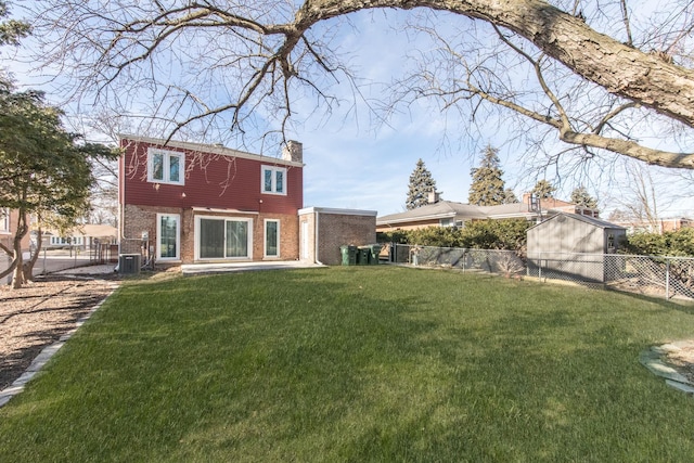 rear view of property with a lawn, a fenced backyard, brick siding, and a chimney