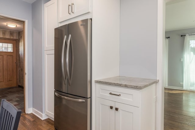 kitchen featuring dark wood finished floors, white cabinetry, freestanding refrigerator, light stone countertops, and a healthy amount of sunlight