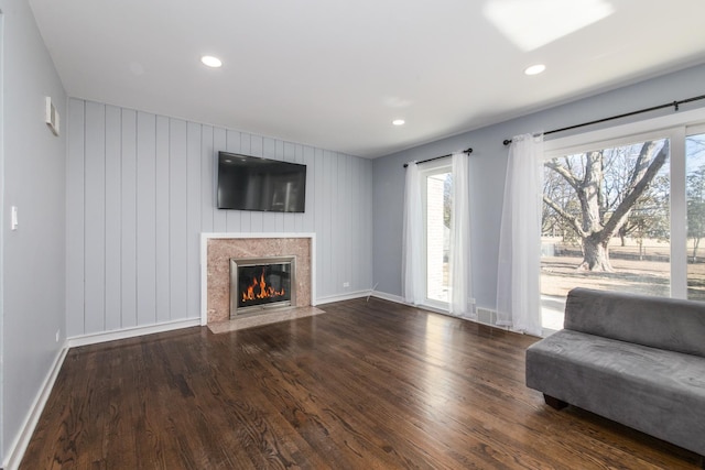 unfurnished living room with recessed lighting, wood finished floors, baseboards, and a premium fireplace