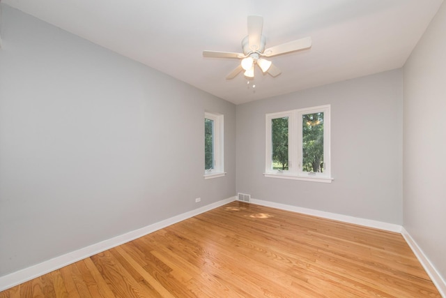 spare room with a ceiling fan, visible vents, light wood-style floors, and baseboards