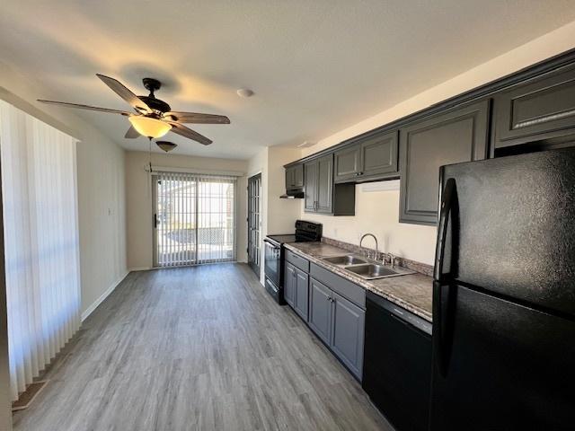 kitchen featuring baseboards, light wood finished floors, ceiling fan, a sink, and black appliances