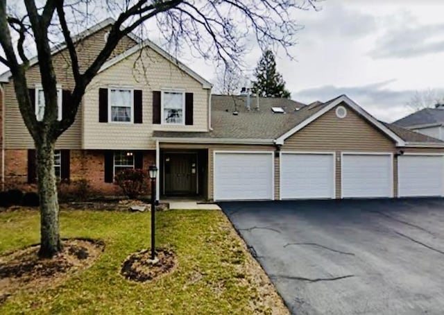 view of front of property with aphalt driveway, a front yard, and a garage