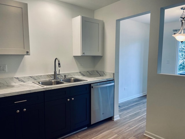 kitchen with baseboards, white cabinetry, a sink, dishwasher, and light wood-type flooring