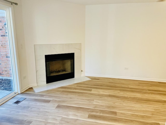 unfurnished living room with light wood finished floors, visible vents, a fireplace, and baseboards