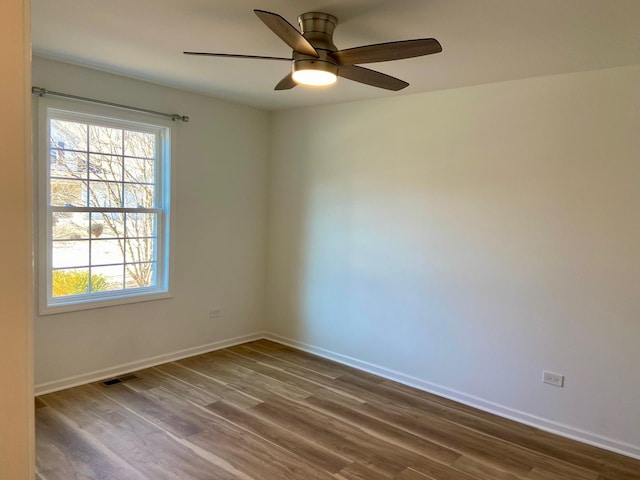 empty room with dark wood finished floors, visible vents, baseboards, and ceiling fan