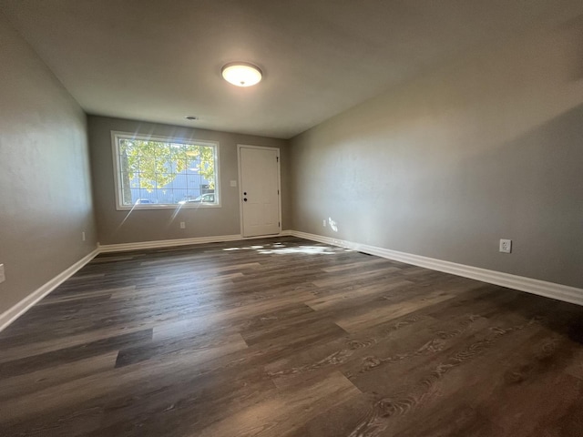 empty room featuring baseboards and dark wood finished floors