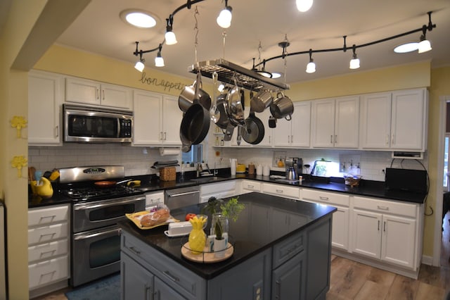 kitchen featuring a sink, stainless steel appliances, dark countertops, and white cabinetry