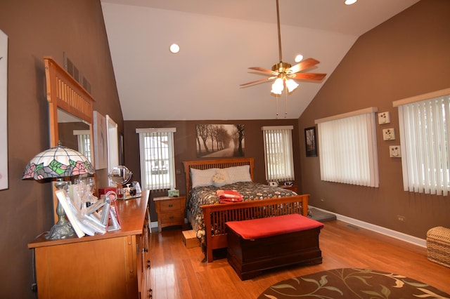 bedroom with visible vents, baseboards, light wood-type flooring, and high vaulted ceiling