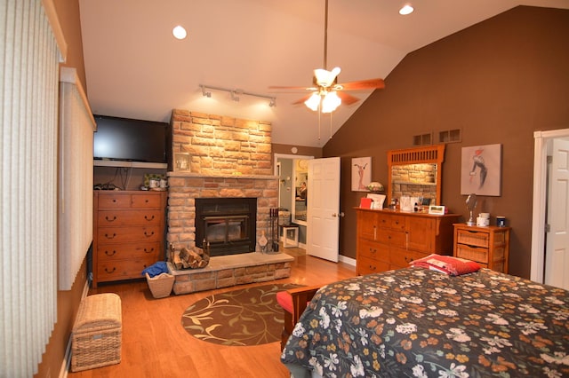 bedroom featuring a stone fireplace, lofted ceiling, recessed lighting, and wood finished floors