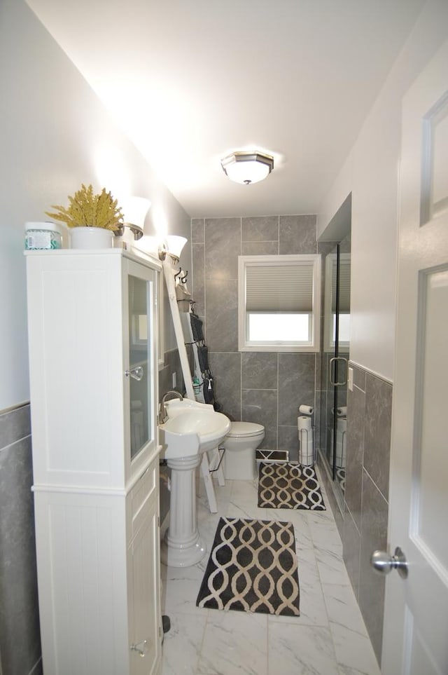 full bath with marble finish floor, tile walls, a shower stall, and toilet