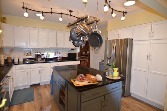 kitchen with dark countertops, stainless steel fridge, and white cabinets