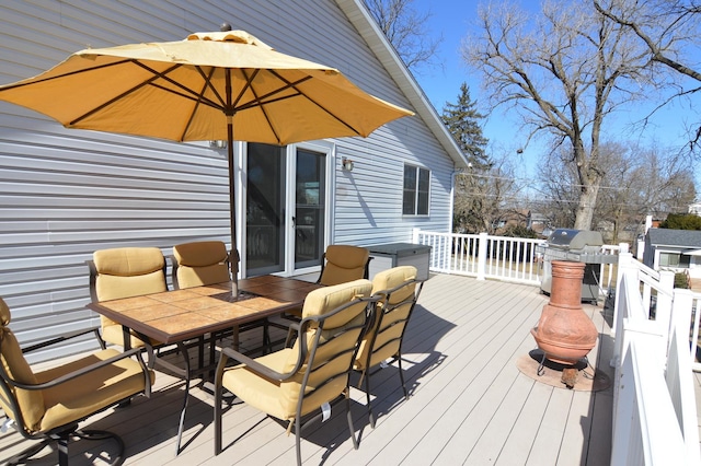 wooden deck featuring outdoor dining area and a grill