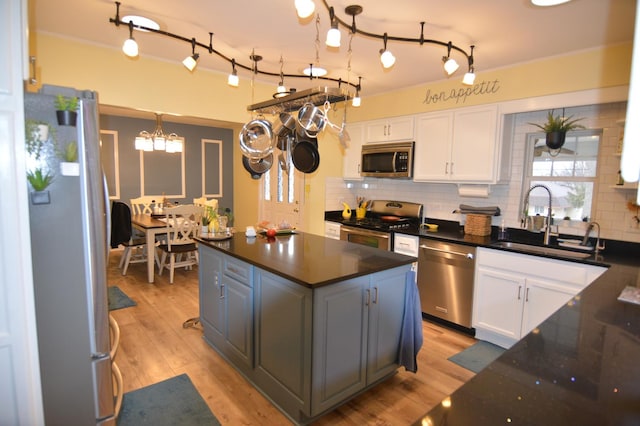 kitchen featuring appliances with stainless steel finishes, white cabinetry, light wood-type flooring, and a sink