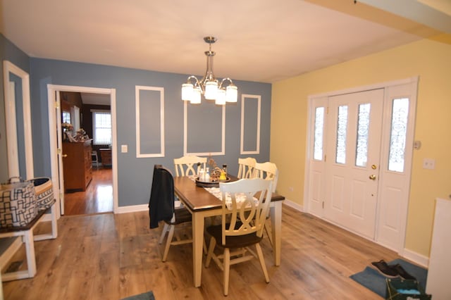 dining room with an inviting chandelier, light wood-style floors, and baseboards