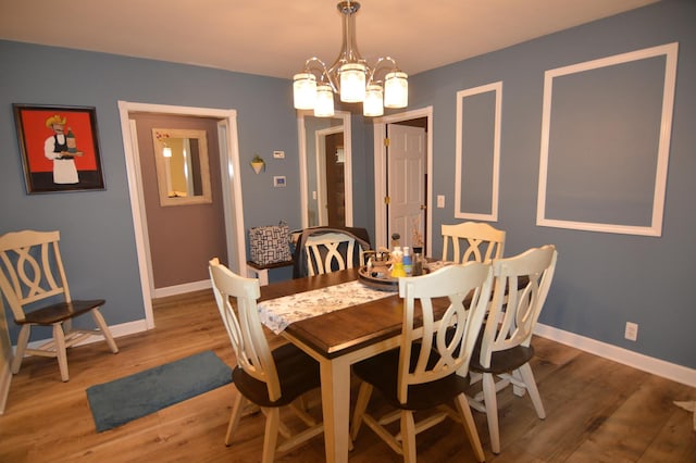 dining room featuring baseboards, an inviting chandelier, and wood finished floors