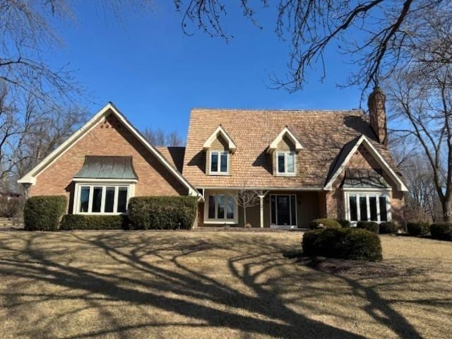 cape cod-style house with a front lawn and a chimney