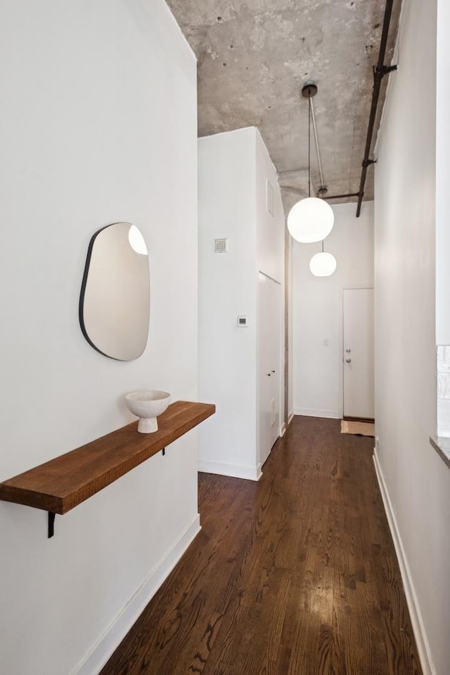 hallway featuring dark wood finished floors, visible vents, and baseboards